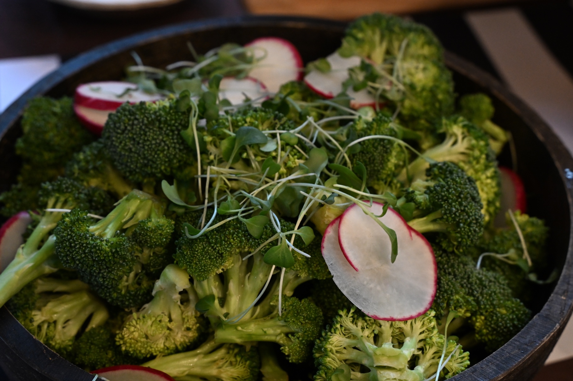 Wooden bowl of broccoli, radish and microgreens