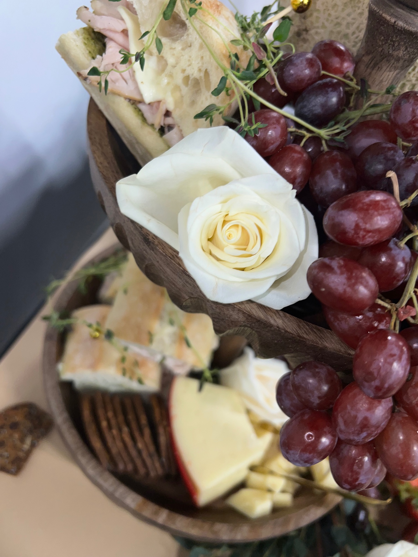 Close-up of tiered board with roses, grapes and panini bites